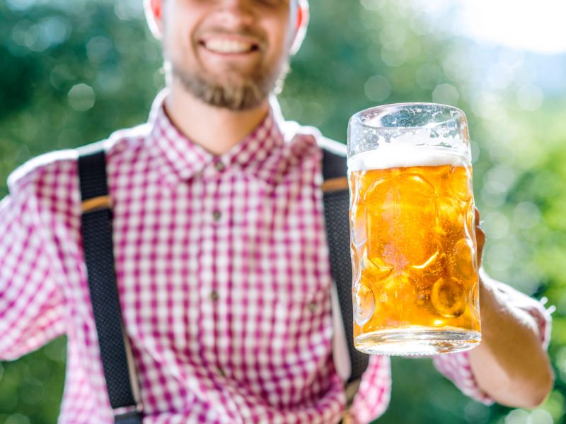 Unrecognizable man in traditional bavarian clothes holding mug of beer. Oktoberfest.